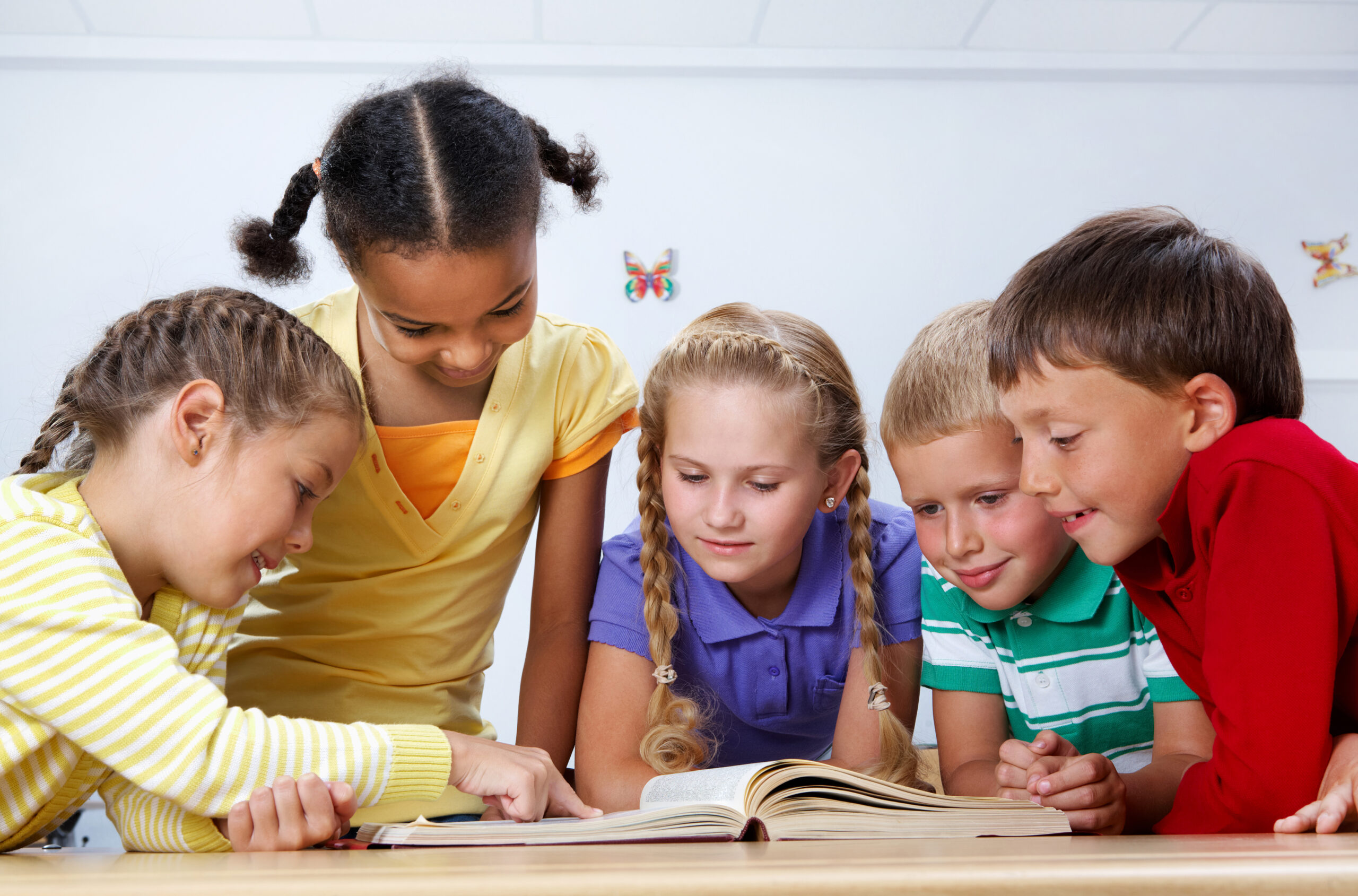 Portrait of pupils looking at page of encyclopaedia at reading lesson