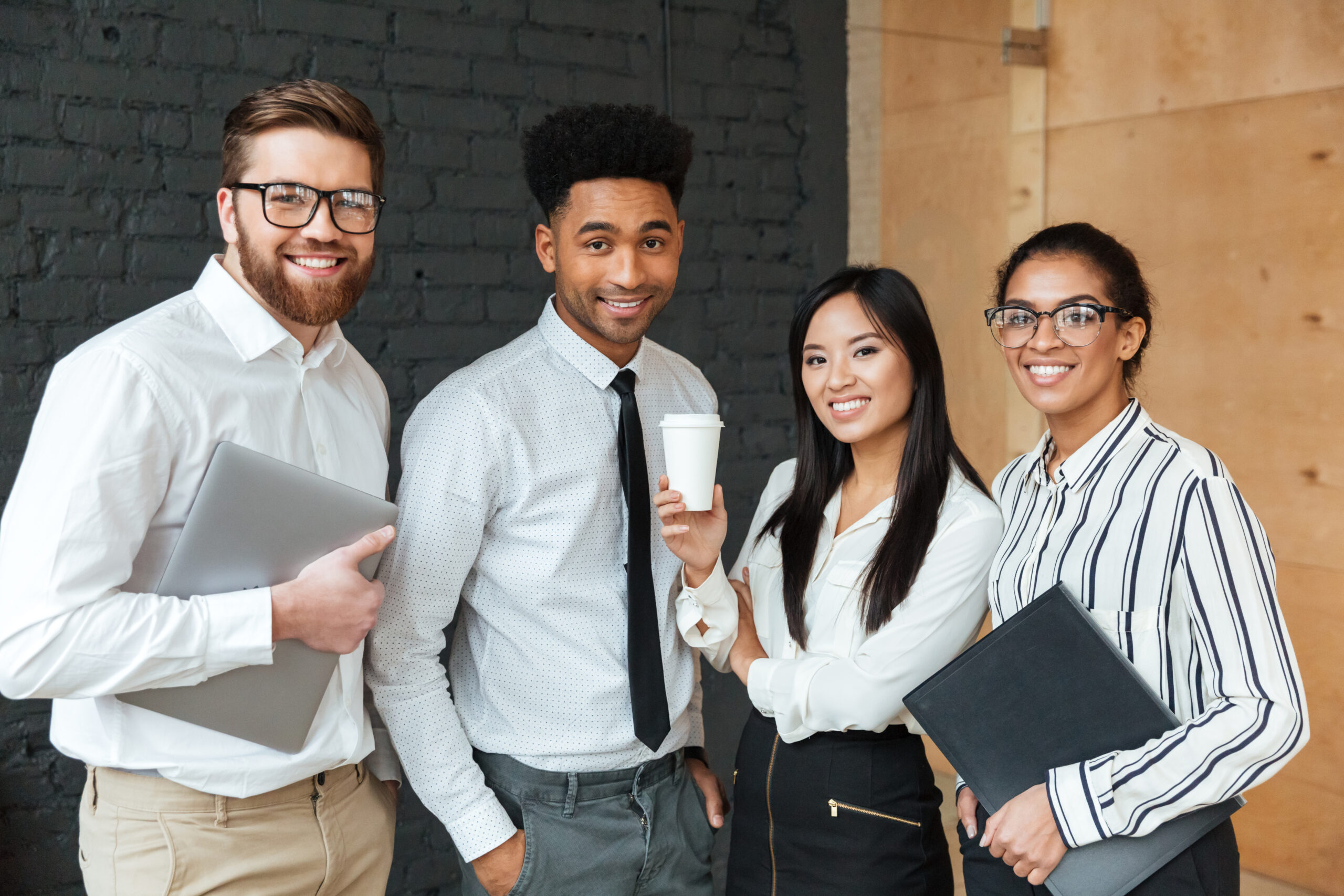 Photo of cheerful young business colleagues indoors coworking. Looking camera.